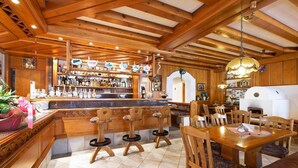 Ein Holzinterieur mit Barbereich, Barhocker, einem Esstisch mit Stühlen und einem weißen Gerät im Hintergrund.