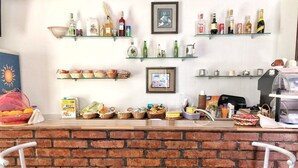 A bar area with a brick wall, two red bar stools, shelves with bottles and glasses, and a framed picture on the wall. - Populus (Syracuse)