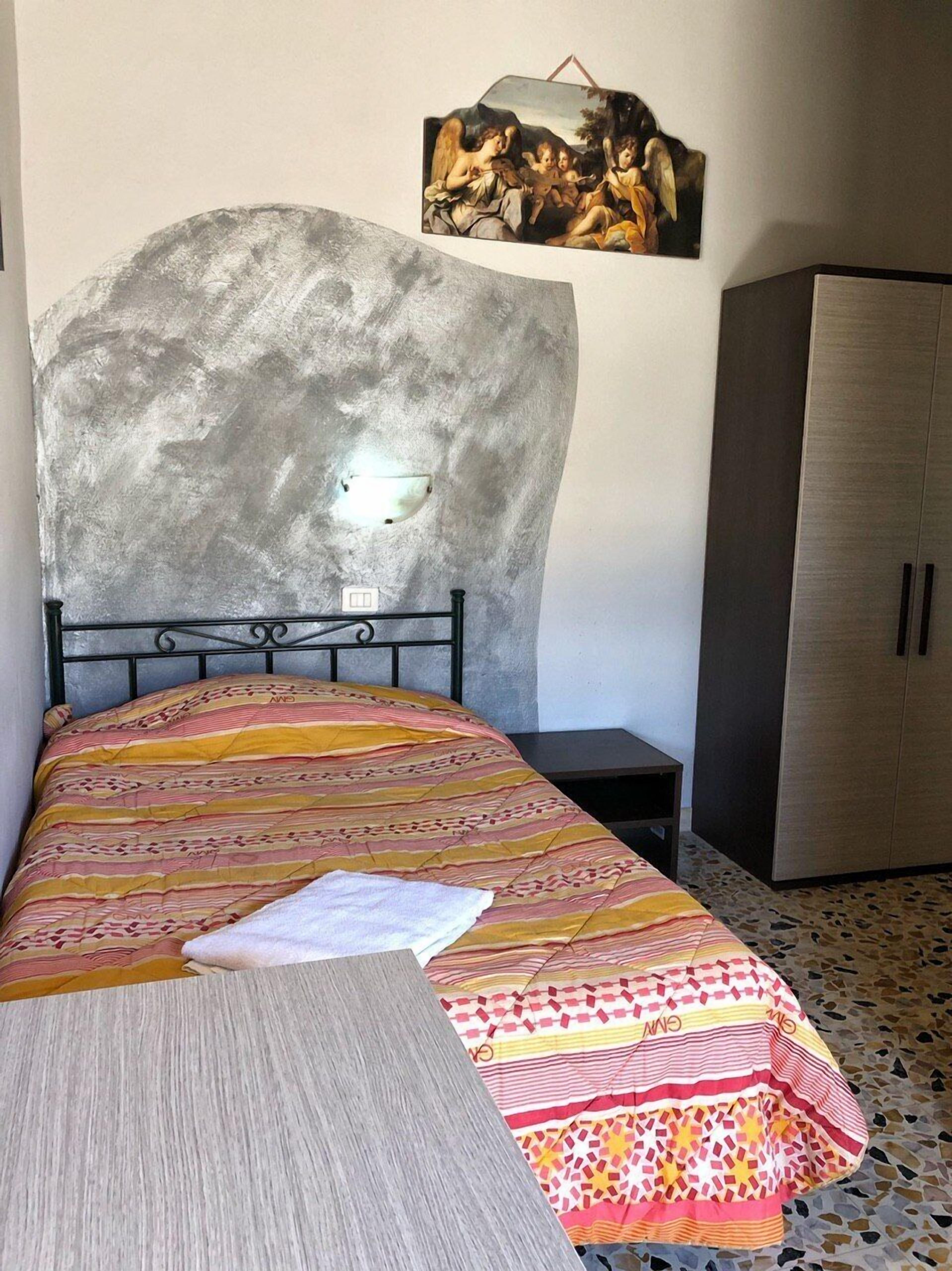 Un dormitorio con cama, cabecero, armario y una obra de arte colgada en la pared.