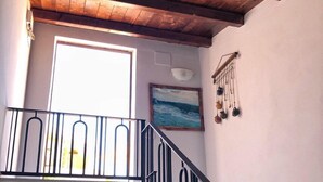 A wooden staircase with black railings leading to a landing. A window with a view of the outdoors is visible on the landing. - Populus (Syracuse)