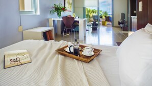 A hotel room with a bed, a breakfast tray with coffee and tea, a book, and a desk with a chair and a plant. - Nereids (Sitia)