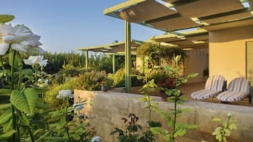 Une terrasse agrémentée d’une pergola, de coins salon extérieurs et d’une végétation luxuriante.
