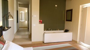Habitación de hotel con una cama grande, una lámpara de noche, un baño con bañera y un tapete a rayas.