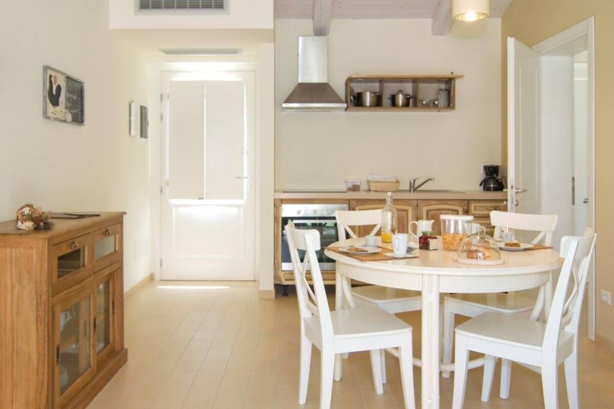 A kitchen with white cabinets, a stove, and a dining table with white chairs.