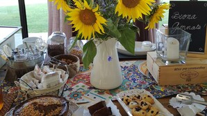 Una mesa con diversos alimentos, incluyendo un pastel, galletas y un jarrón con girasoles.