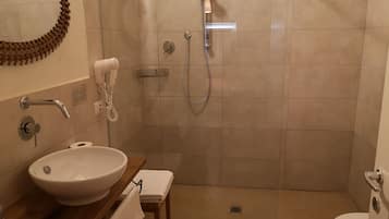 Un baño con lavamanos, espejo, toallero, ducha con cabezal de ducha manual y retrete.