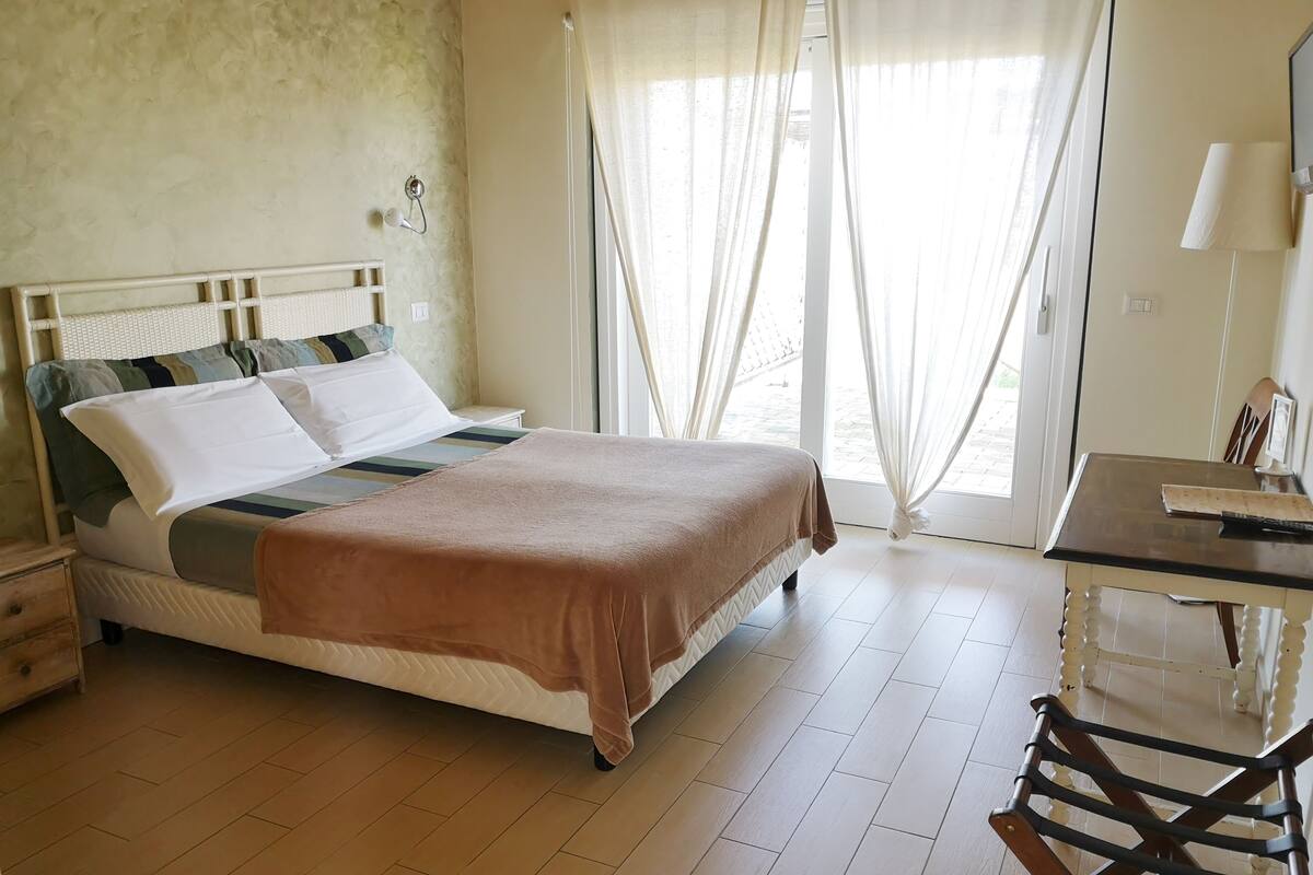 A neatly arranged bedroom with a bed, a desk, and a chair.