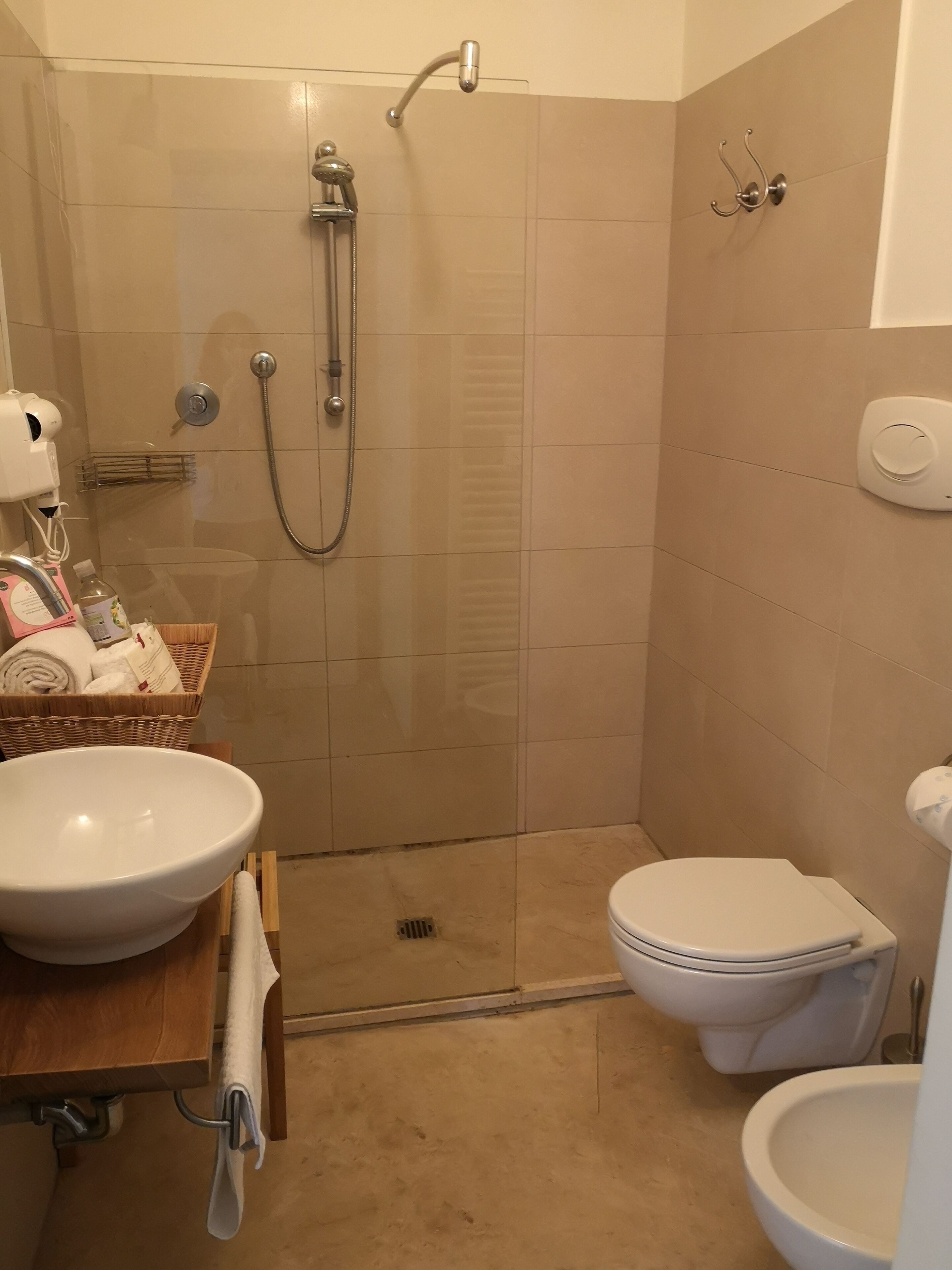 Un baño con ducha, inodoro, lavabo y una pequeña cesta de mimbre con toallas.