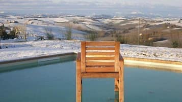 Una silla de madera en una piscina, con un paisaje nevado al fondo.
