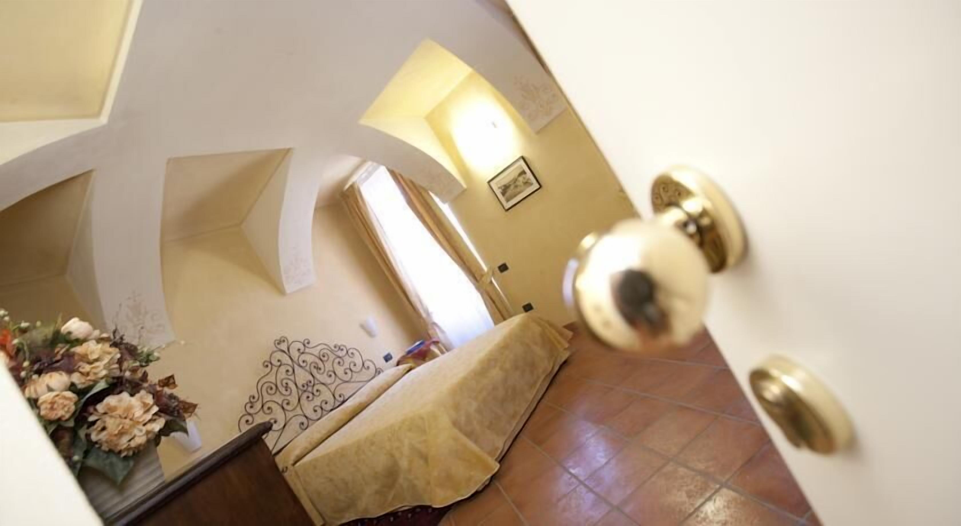 Una stanza con un letto, una parete decorativa e una porta con maniglia in ottone.