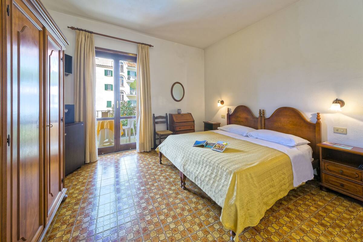 A bedroom with a bed, wooden wardrobe, and a balcony door.