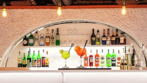 A bar area with a variety of liquor bottles and glasses, including martinis and cocktails. - Hotel San Valentino (Ischia)