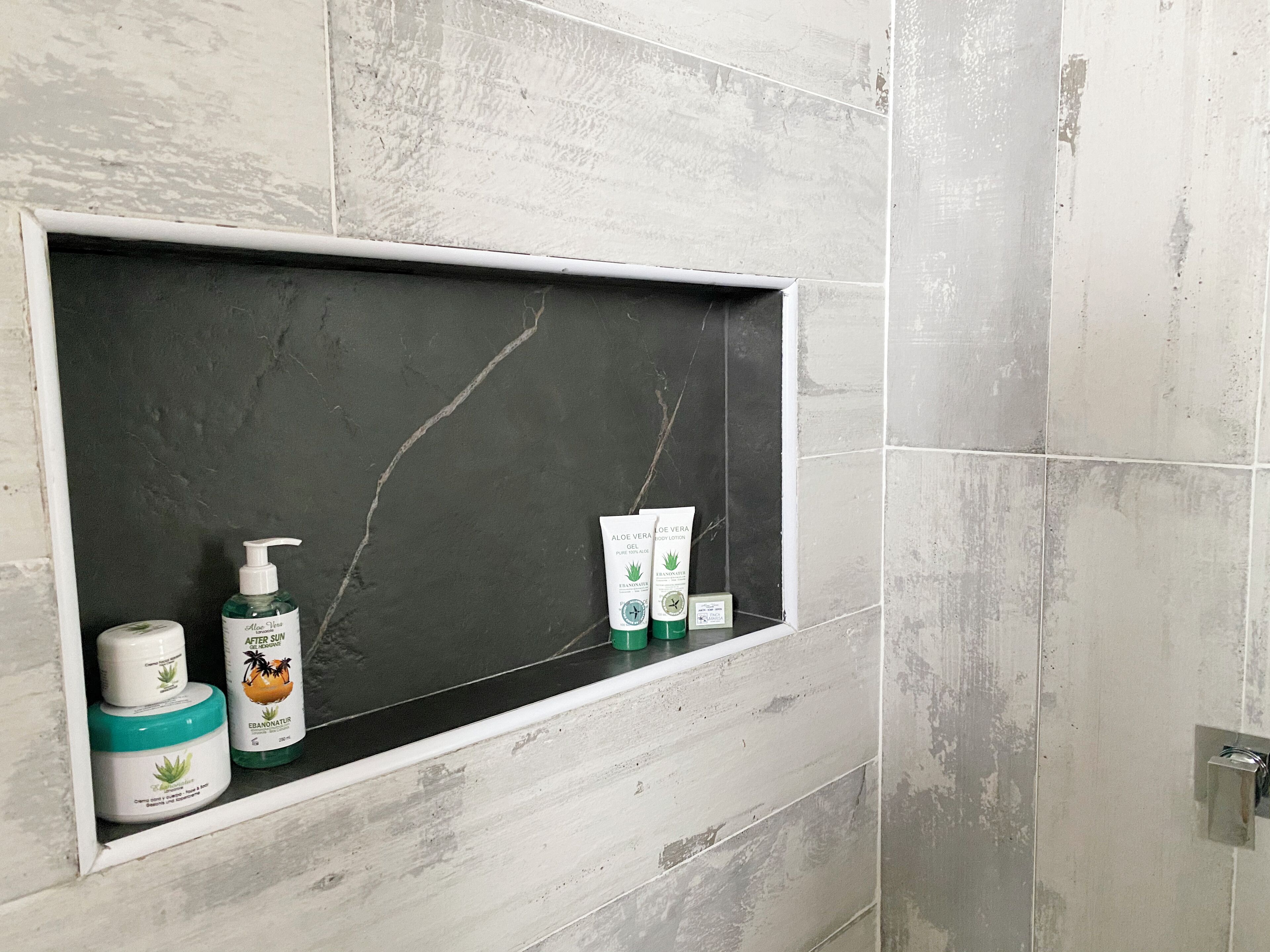 A bathroom with a shelf holding toiletries.