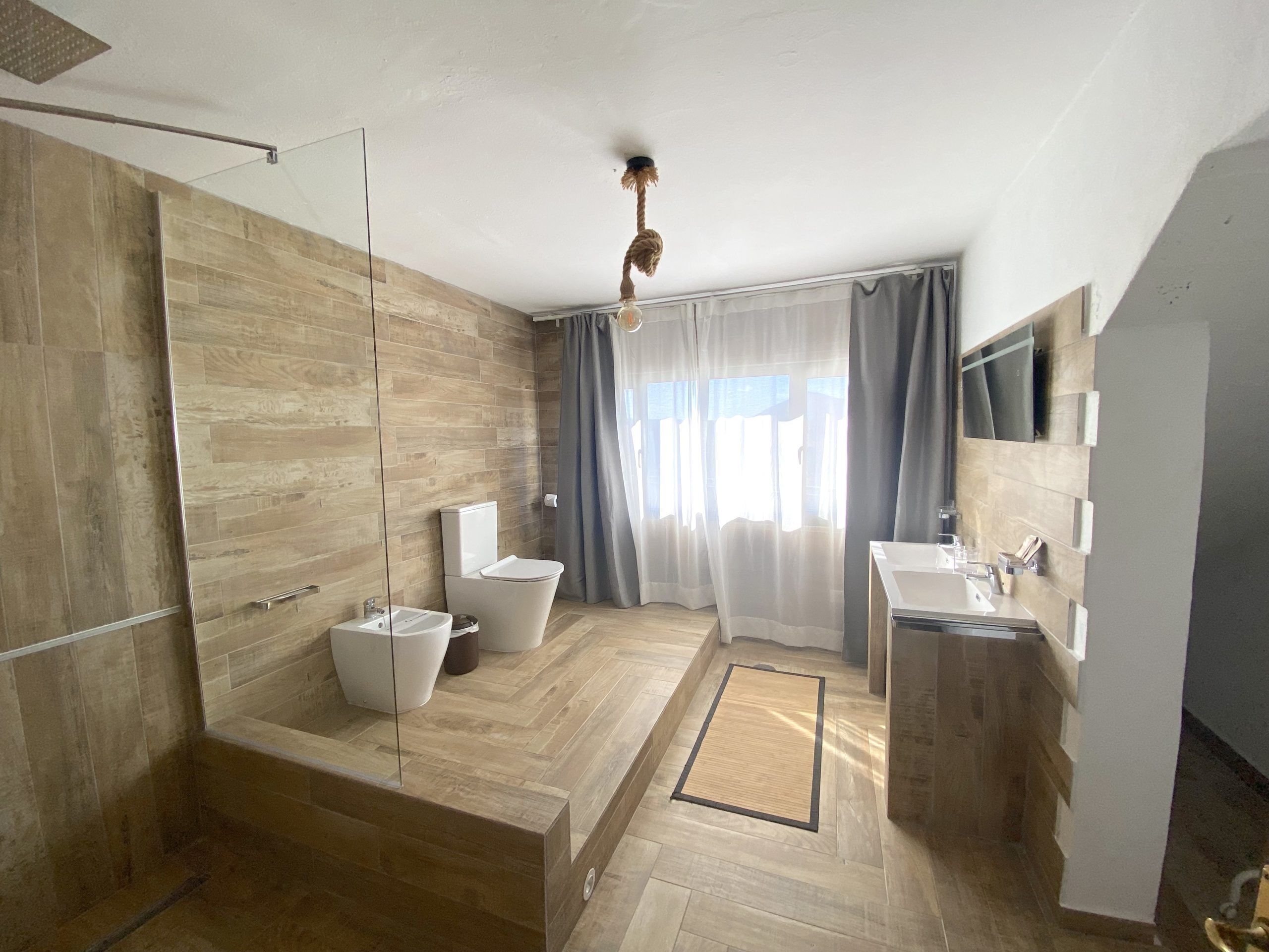 A modern bathroom with a shower, toilet, and sink.