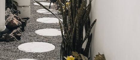 Un sendero con piedras circulares que conducen a un edificio con una estructura de madera en la parte superior.