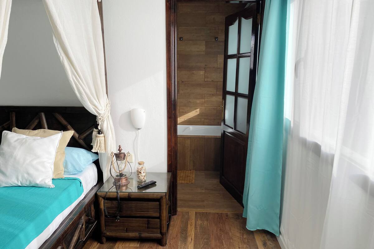 Une chambre à coucher avec un lit, une table de chevet et une vue sur la salle de bain.