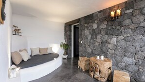Una sala moderna con pared de piedra, un sofá curvo y una mesa de centro de madera con velas.
