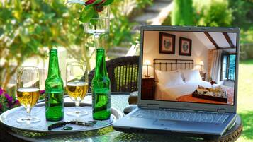 A laptop on a table with a tray of drinks and a bottle of beer.