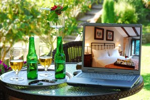 A laptop on a table with a tray of drinks and a bottle of beer.
