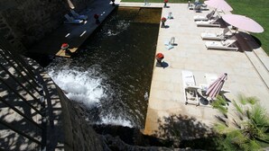 A rooftop pool with a waterfall feature, lounge chairs, and umbrellas. - Rusticae Torre do Río (Caldas de Reis)