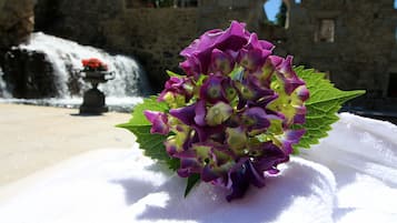 A bouquet of purple flowers on a white surface with a stone building in the background.