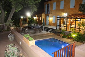 A pool area with a wooden deck, outdoor furniture, and a glass-enclosed dining area. - Cap Serein Guest House (Cape Town)