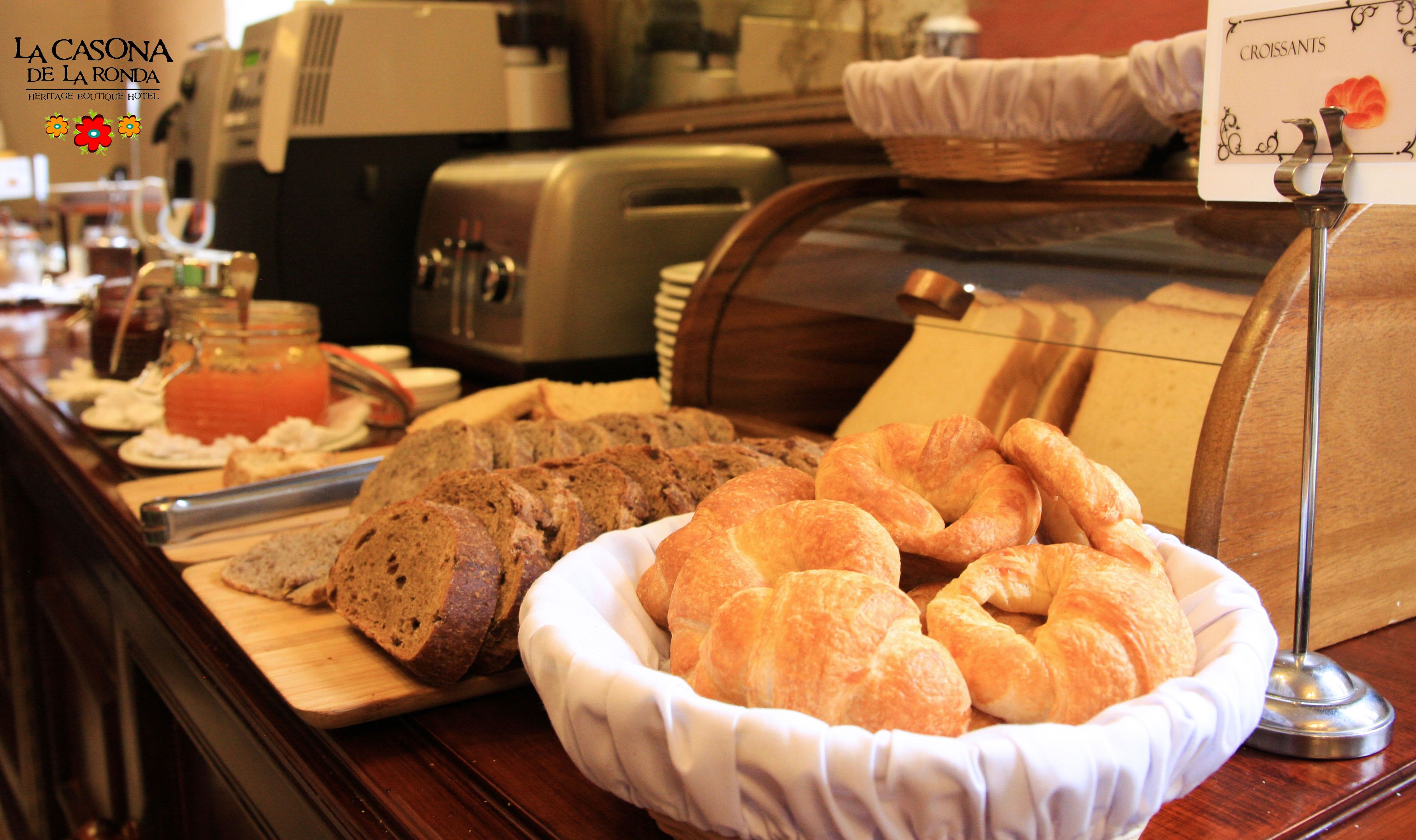 Un bufé de desayuno con pan, cruasanes y un cartel que indica cruasanes.