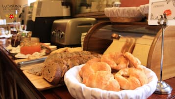 A breakfast buffet with bread, croissants, and a sign for croissants.