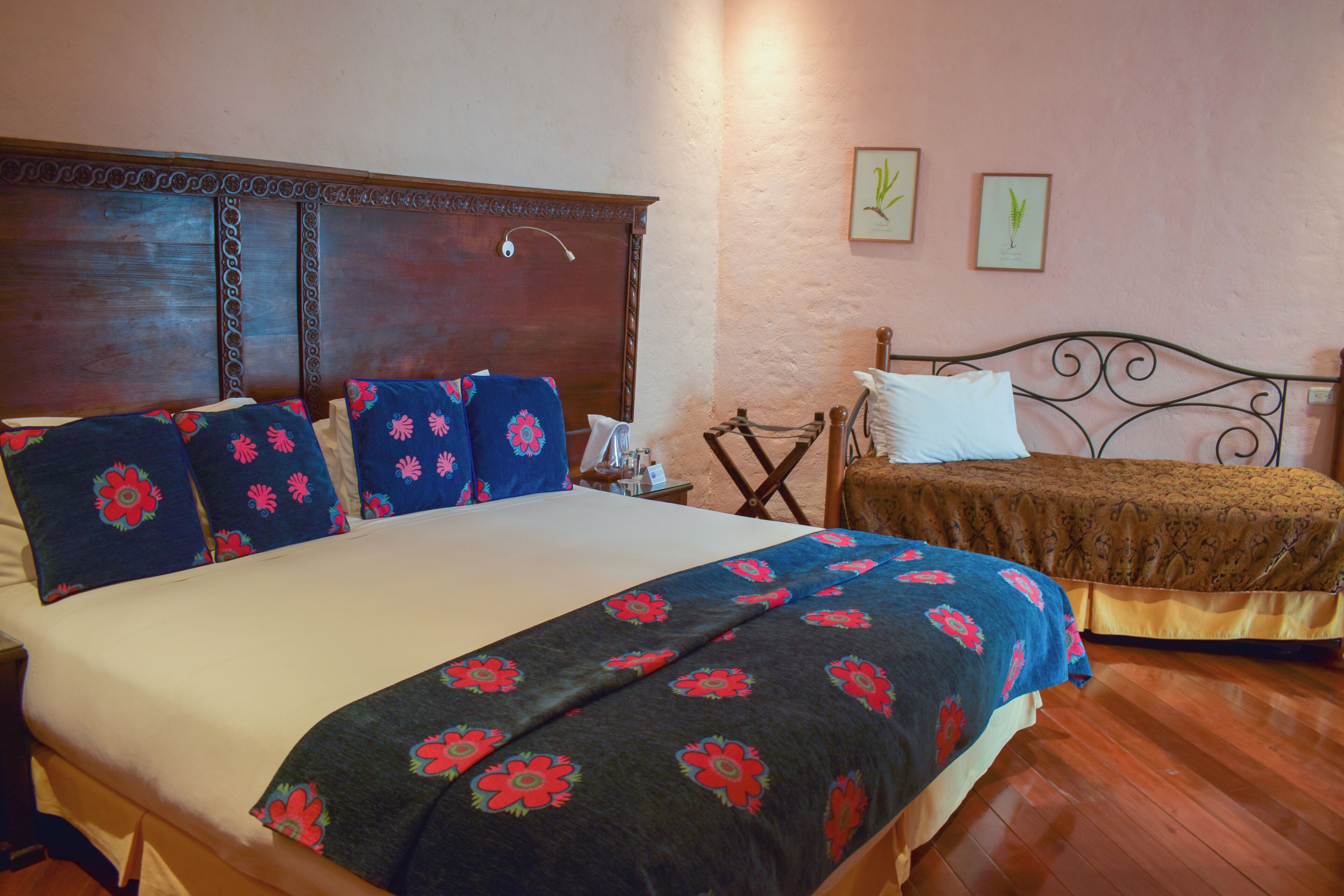 Quarto com uma cama grande, uma cama menor e uma mesa de cabeceira com abajur.