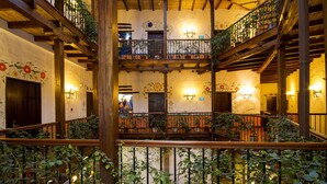 Un atrio de varios niveles con balcones de madera, arte floral decorativo en la pared y plantas en macetas.