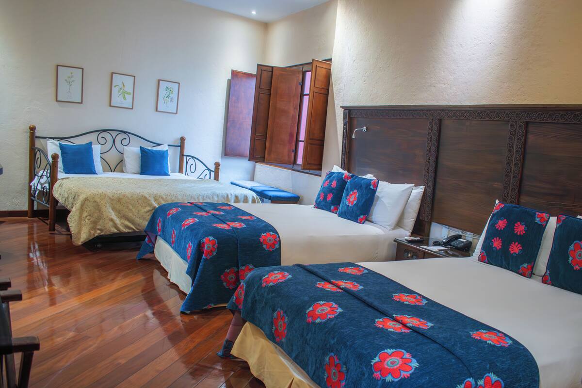Habitación de hotel con dos camas, suelo de madera y cabecero de madera.