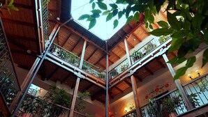 Un atrio de varios niveles con vigas de madera, balcones y plantas en macetas.