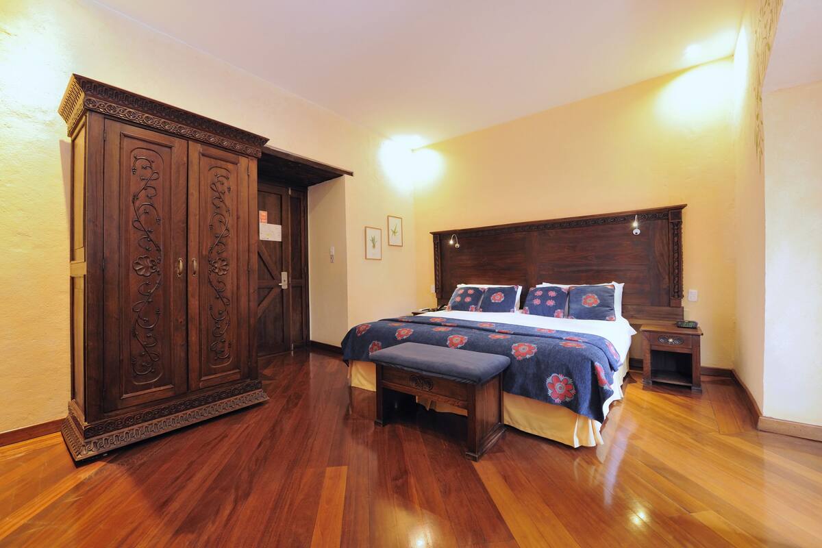 Un dormitorio con un armario grande de madera, una cama con ropa de cama floral y una mesita de noche.