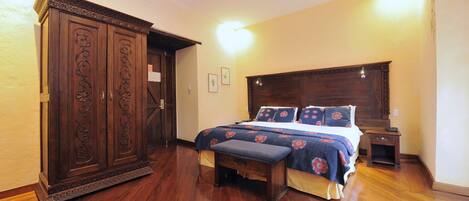 Un dormitorio con un armario grande de madera, una cama con ropa de cama floral y una mesita de noche.