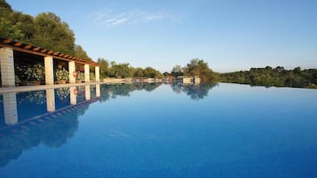 Una piscina techada, una piscina al aire libre, sombrillas