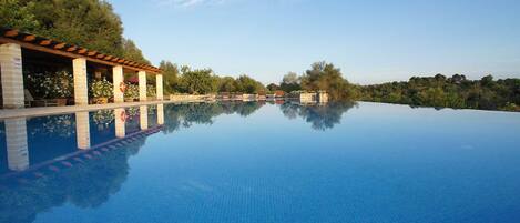 Una piscina cubierta, una piscina al aire libre, sombrillas, tumbonas
