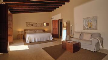 A bedroom with a bed, a sofa, a coffee table, and a painting on the wall.
