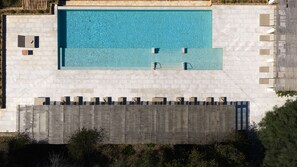 A rectangular pool with a clear blue water surface, surrounded by a stone deck and a low stone wall.