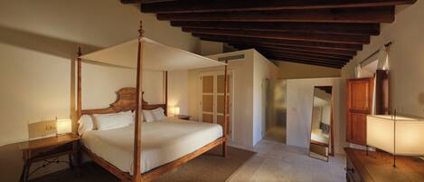 A four-poster bed with a wooden frame, a bedside table with a lamp, and a mirror on the wall.