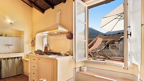 A kitchen with a view of a damaged building outside. - Corte Paganini (Ricco del Golfo di Spezia)