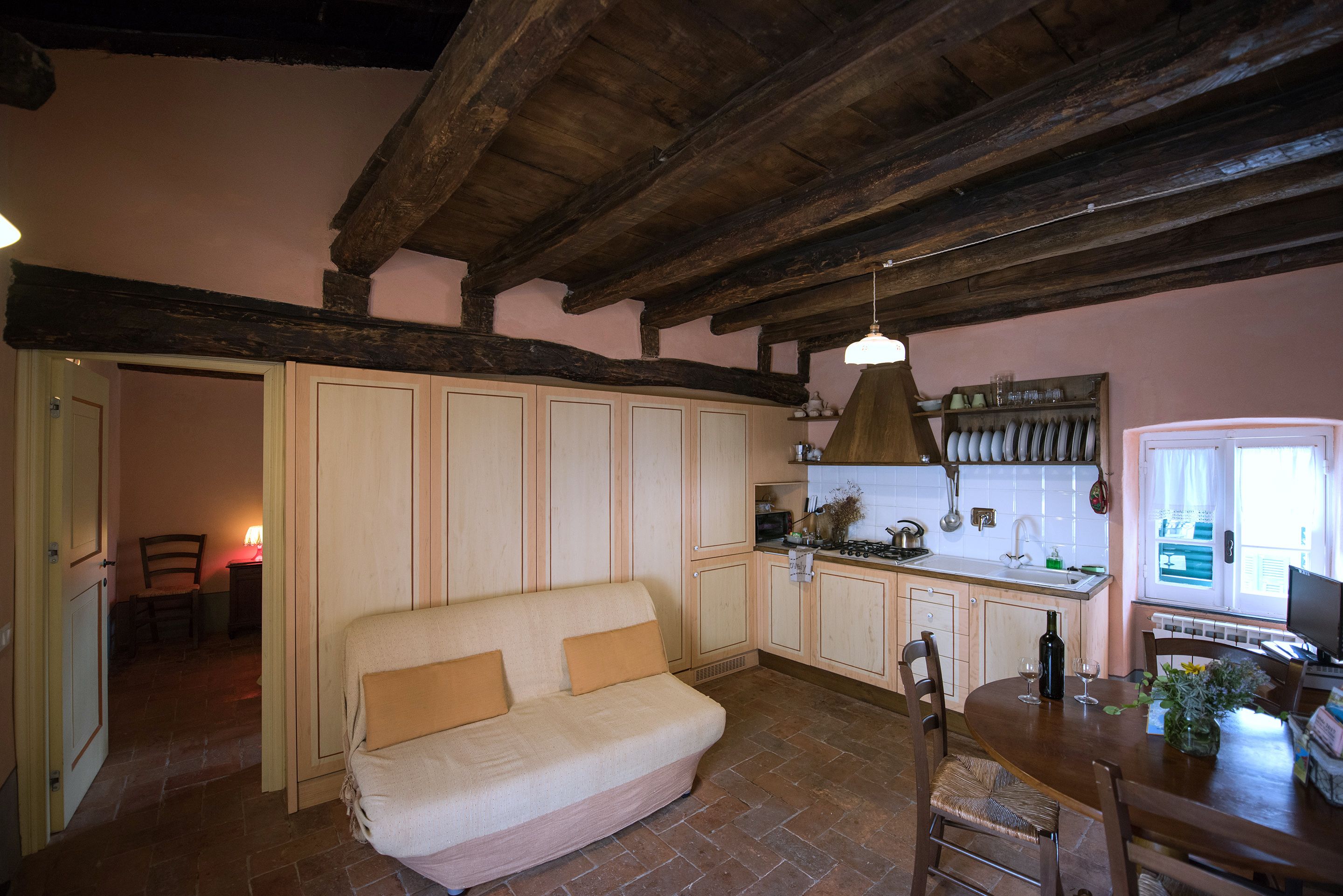 Een gezellige keuken met een houten plafond, een bank en een eettafel met stoelen.