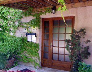 A wooden door with a glass panel, a wooden pergola, and a wall with a menu sign. - Logis Le Mas des Collines (Tourtour)