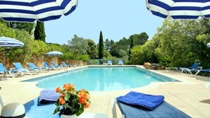 Una piscina con tumbonas y sombrillas a rayas.