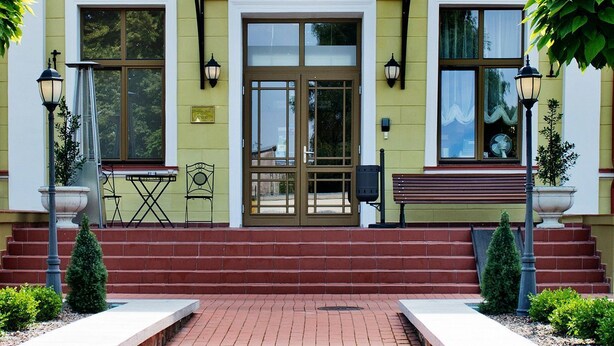 L’entrée d’un hôtel, avec une façade jaune, une double porte et un petit escalier menant à l’entrée.