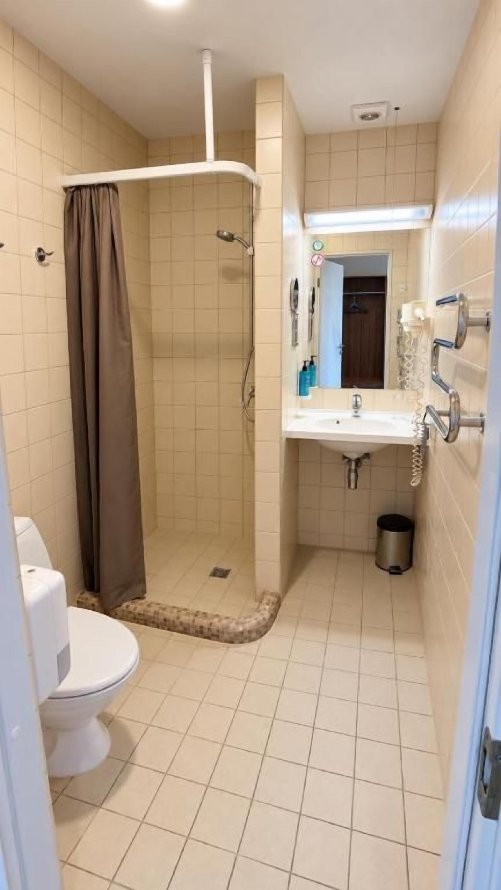 Un baño con ducha, inodoro, lavamanos y espejo.