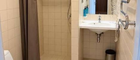 Un baño con ducha, inodoro, lavamanos y espejo.