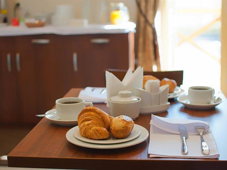 Desayuno con croissants, café y té sobre una mesa de madera.