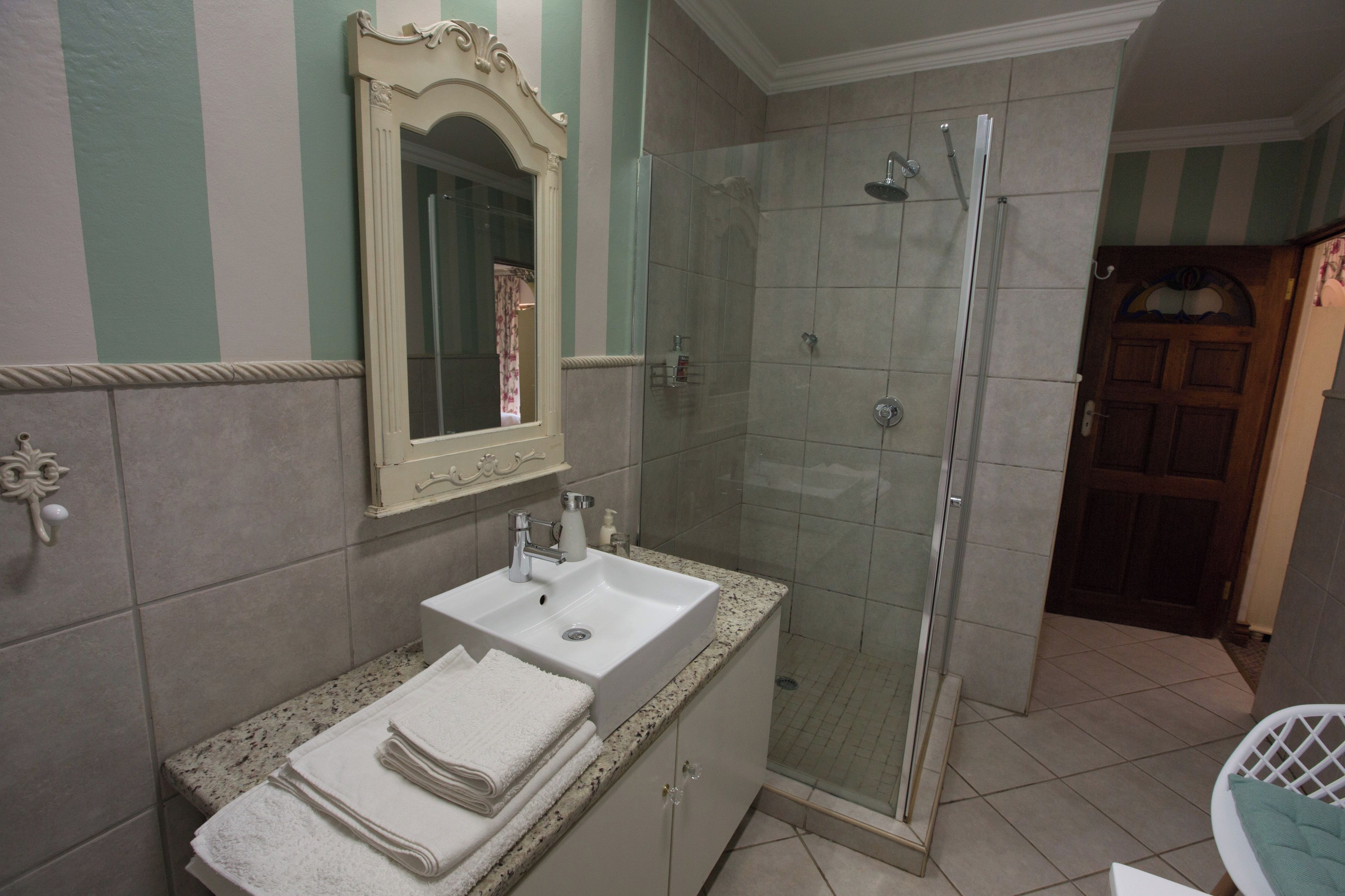 Un baño con lavamanos, espejo y ducha.