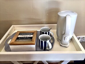 Una bandeja con un libro, dos tazas a rayas y una cafetera.
