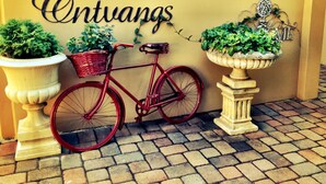 Een rode fiets geparkeerd naast een muur met het bord 'Ontuanas'.